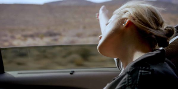 Girl with her hand out the window driving through Red Rock National Conservation Area